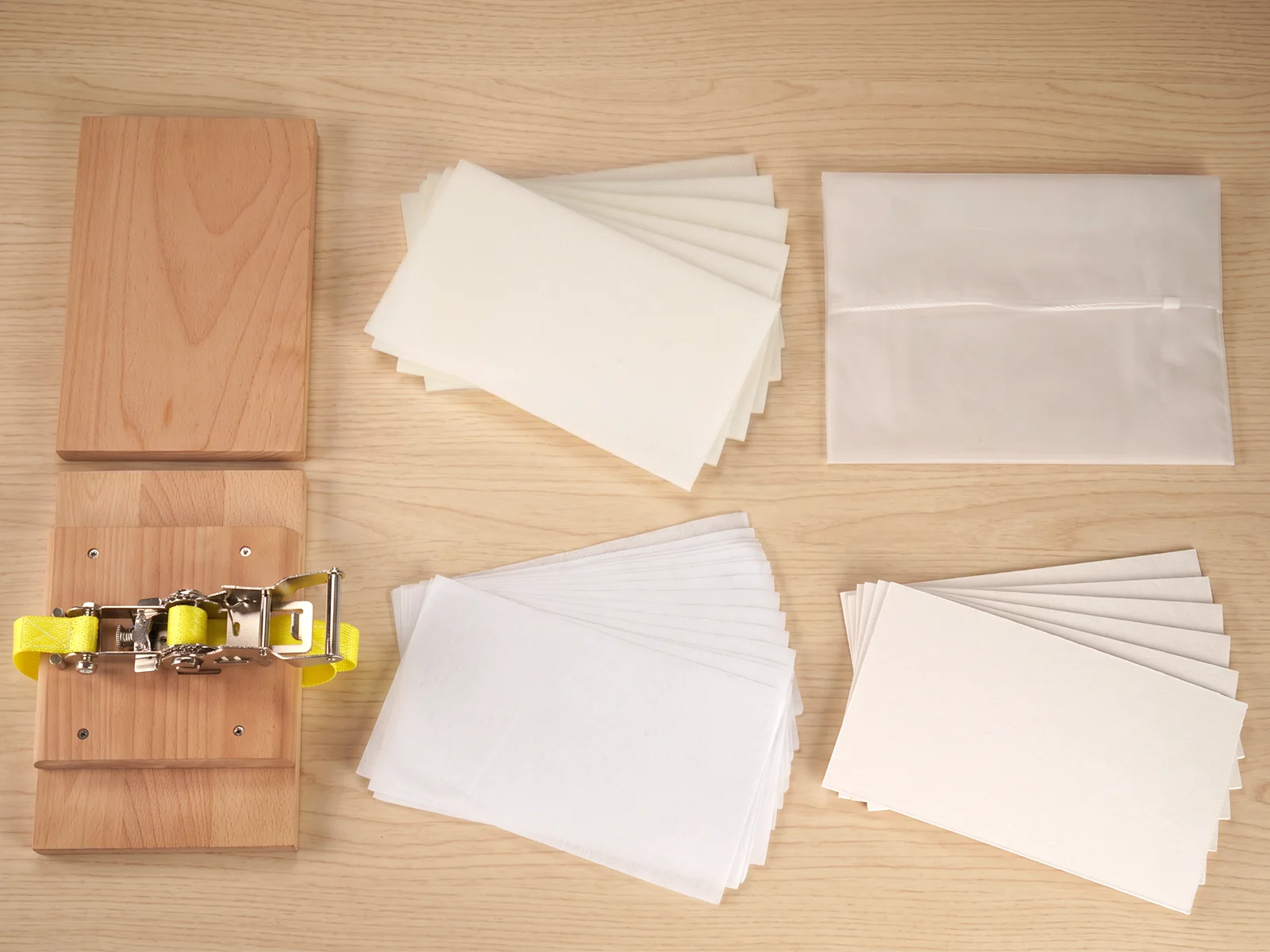 The full set laid out flat: boards, ratchet, yellow strap, foam sheets, lining paper, blotting boards and the zip bag.