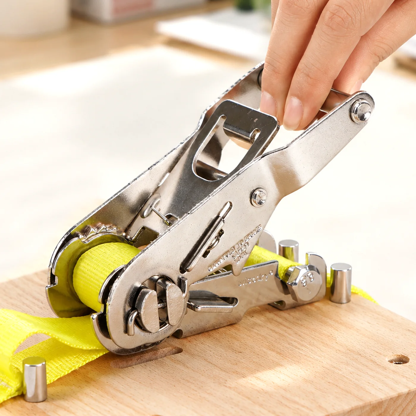 Close-up of a hand on the steel ratchet handle with the yellow strap.