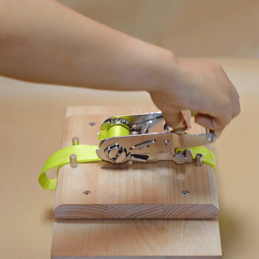 Animated: the release handle lifted and the ratchet handle pressed down, the strap going slack.